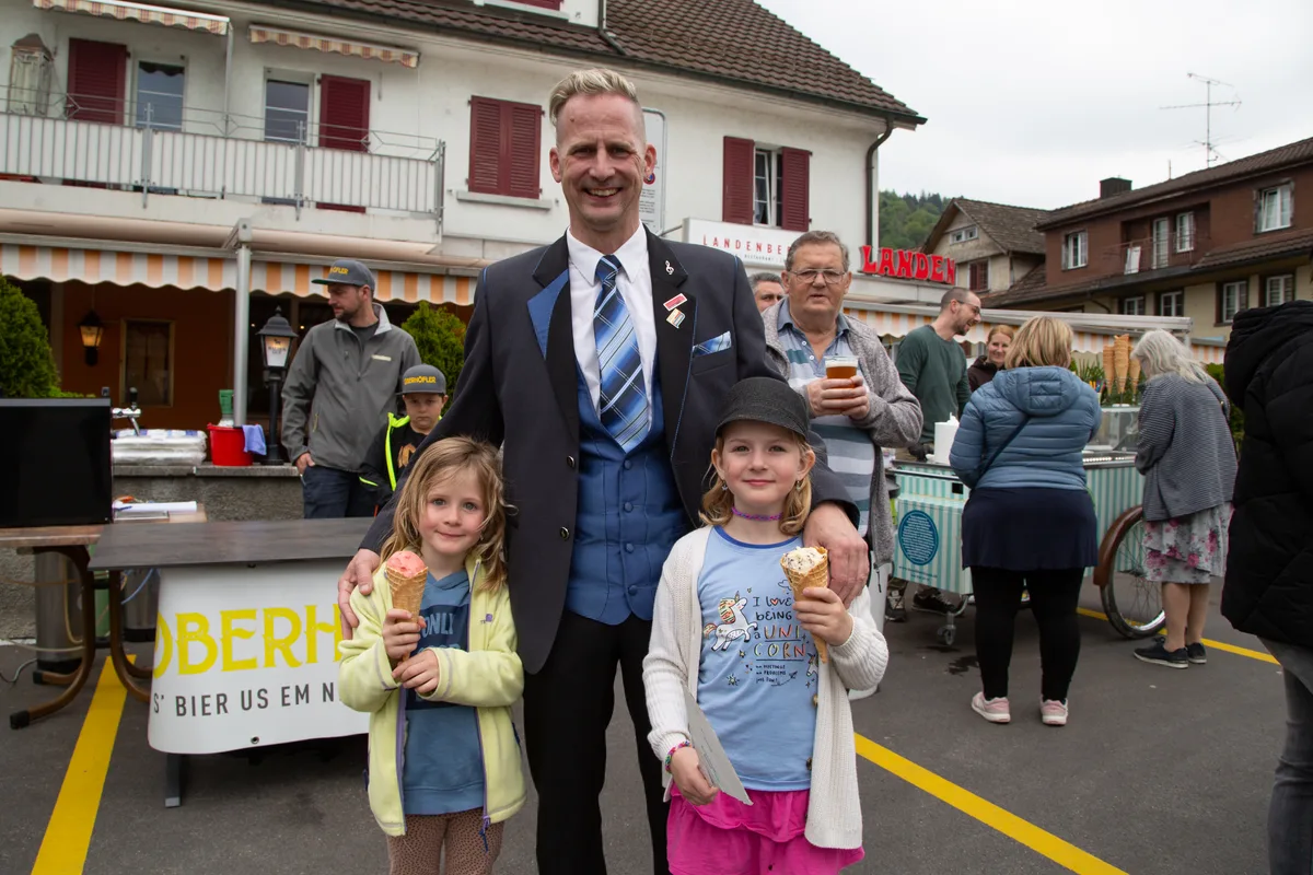 Der neue Kreisel ist ein Grund zum Strahlen. Oder liegt es doch eher an der Glace? Man sieht einen Mann mit zwei Mädchen, die eine Glace in der Hand haben.